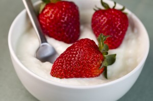 Whole Strawberries in Vanilla yogurt with Spoon in bowl